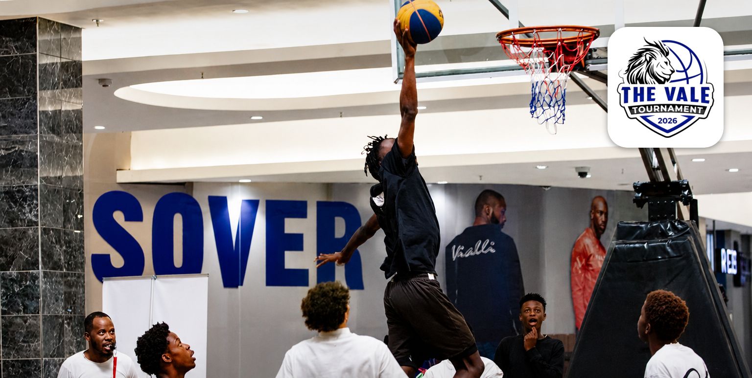 A basketball player reaches towards the indoor basket