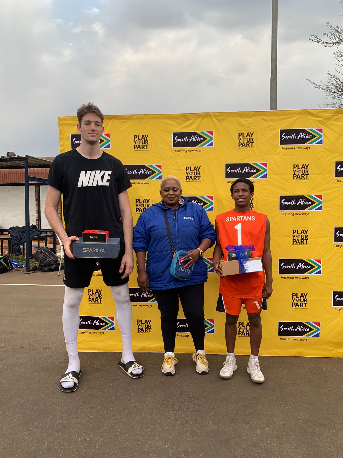 Two young players with their awards alongside a tournament supporter