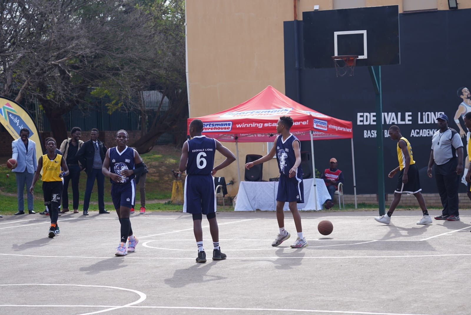 Players in navy jerseys reset beneath the outdoor basket